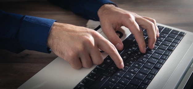 Manos masculinas escribiendo en el teclado de la computadora