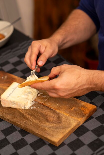manos masculinas esparciendo queso tierno sobre una tostada