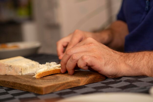 manos masculinas esparciendo queso tierno sobre una tostada