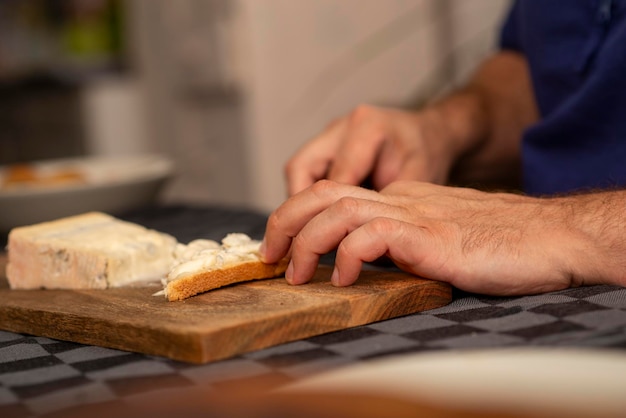 Foto manos masculinas esparciendo queso tierno sobre una tostada