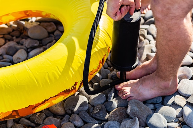 Manos masculinas inflan un aro salvavidas en la playa con una bomba