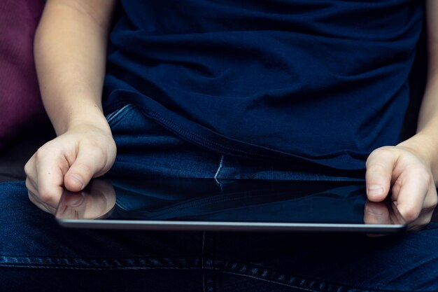 Manos masculinas irreconocibles de la sección media que sostienen la tableta digital sentarse con las piernas cruzadas Mercado de aplicaciones de aprendizaje electrónico