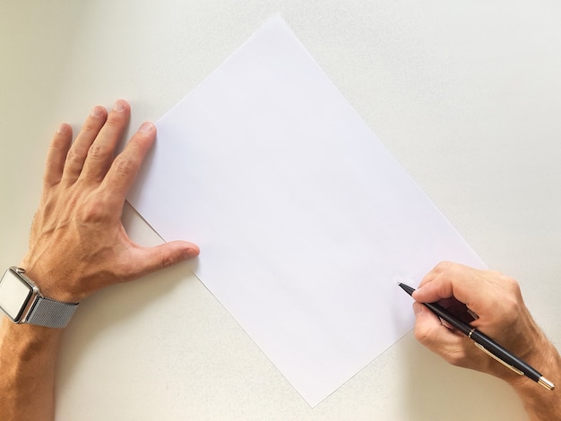 Manos masculinas con un lápiz sobre la hoja de papel