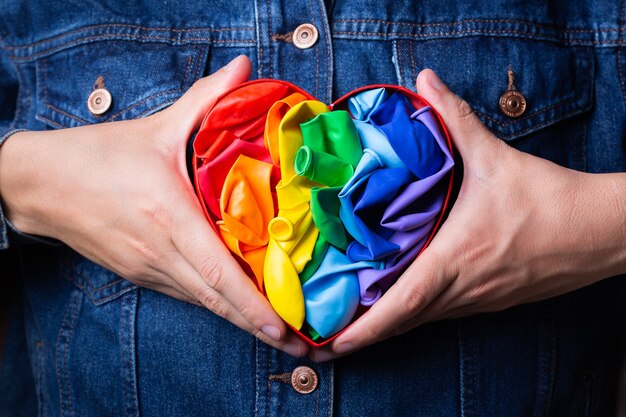 Manos masculinas con el mes del orgullo de la bandera lgbtq del arco iris en forma de corazón