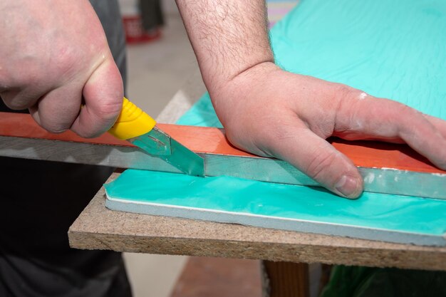 Las manos masculinas miden y cortan el panel sándwich de paneles de yeso con un cuchillo de construcción Reparación de una casa o apartamento Instalación de pendiente Reparación de bricolaje