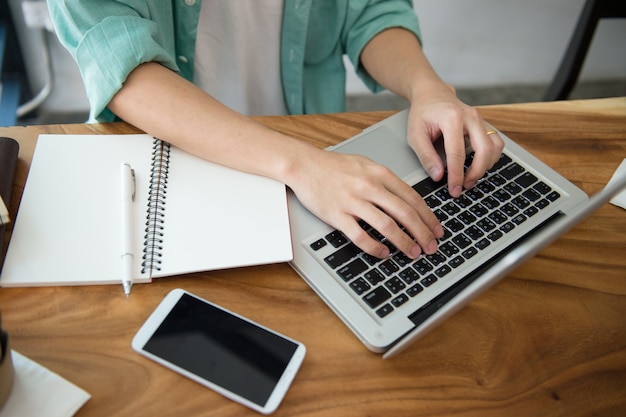 Manos masculinas del negocio que mecanografían en un teclado del ordenador portátil en el escritorio con una taza de café