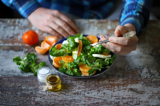 Manos masculinas con un plato de ensalada en la mesa.