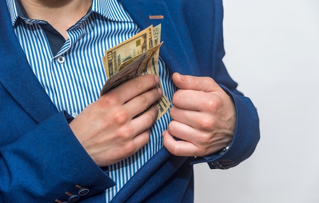 Manos masculinas poniendo billetes de dólar en el bolsillo