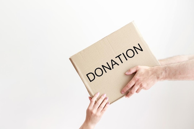 Manos masculinas regalando una caja artesanal con una donación en un fondo blanco