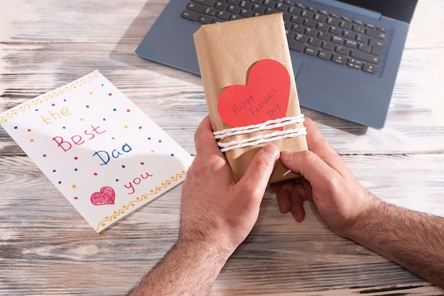 Manos masculinas con regalo envuelto en papel artesanal