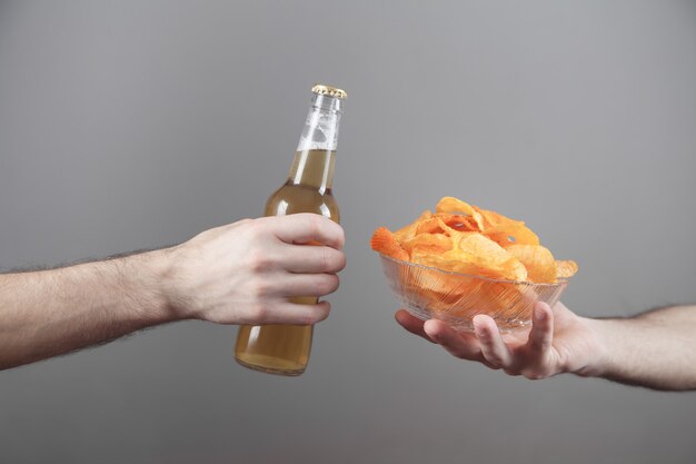 Manos masculinas con sabrosas patatas fritas y cerveza.