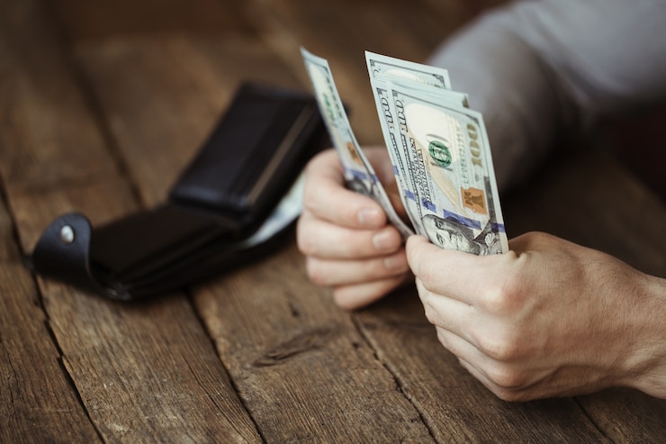 Foto manos masculinas sosteniendo billetes de dólar en mesa de madera antigua