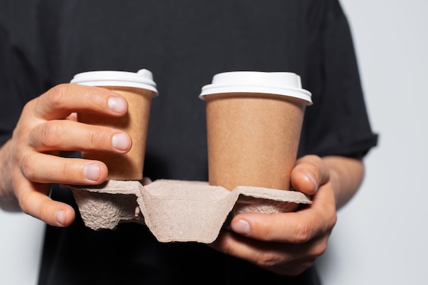 Manos masculinas sosteniendo soporte de cartón de papel con vasos de papel para café