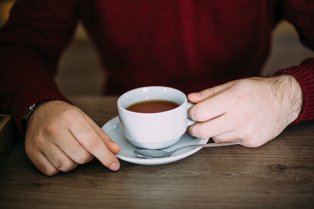 Manos masculinas sosteniendo una taza de té en un café