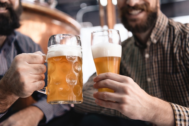 Manos masculinas sostienen cerveza cerveza fresca en vidrio y taza.