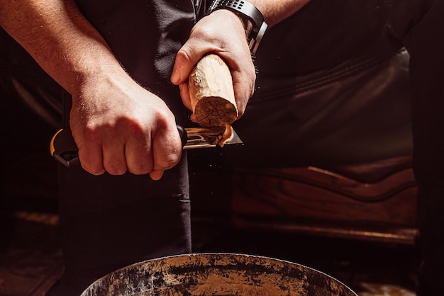 Manos masculinas tallan madera con un cuchillo