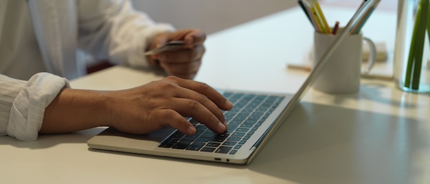 Manos masculinas trabajando en una computadora portátil en el escritorio