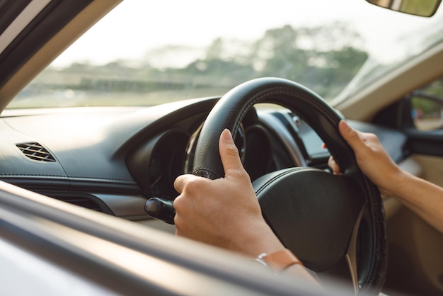 Manos masculinas en el volante a la derecha con vista del lado del país