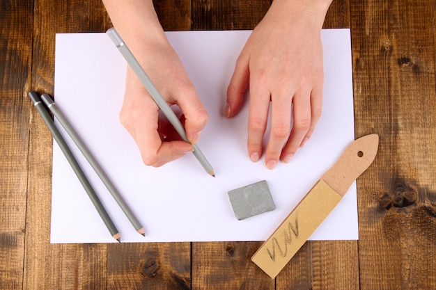 Manos con materiales de arte sobre fondo de madera