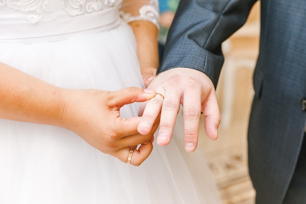 Manos de matrimonio de novios con anillos de boda. Mano de la novia poniendo el anillo de bodas en el dedo del novio. Declaración de amor, primavera. Saludo de la tarjeta de boda. Detalles de la ceremonia de los momentos del día de la boda.