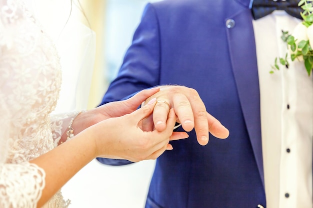 Manos de matrimonio de novios con anillos de boda. Mano de la novia poniendo el anillo de bodas en el dedo del novio. Declaración de amor, primavera. Saludo de la tarjeta de boda. Detalles de la ceremonia de los momentos del día de la boda.