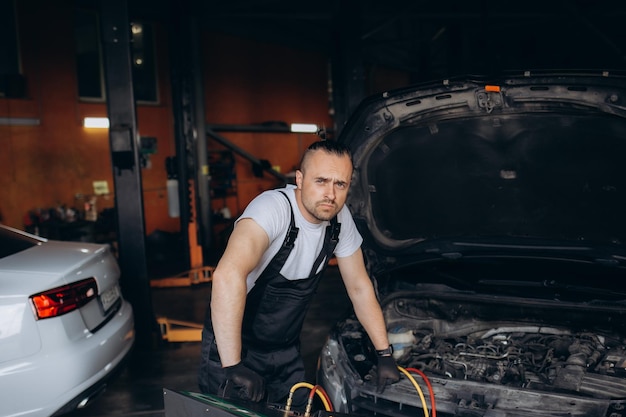 Las manos del mecánico de automóviles incluyen la instalación de recarga del aire acondicionado en el servicio de automóviles