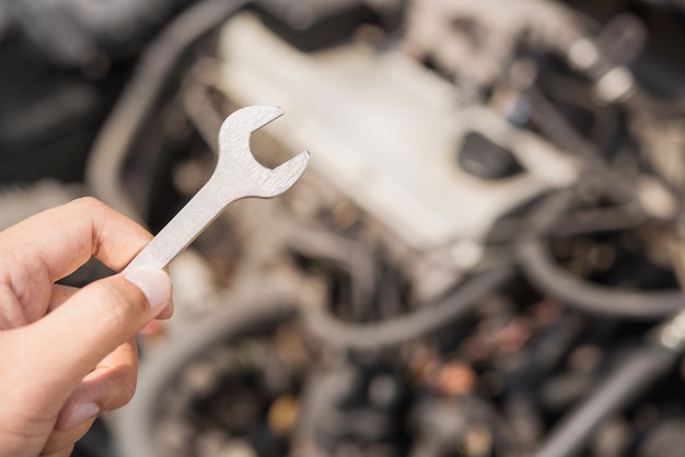 Manos de mecánico de automóviles con llave.