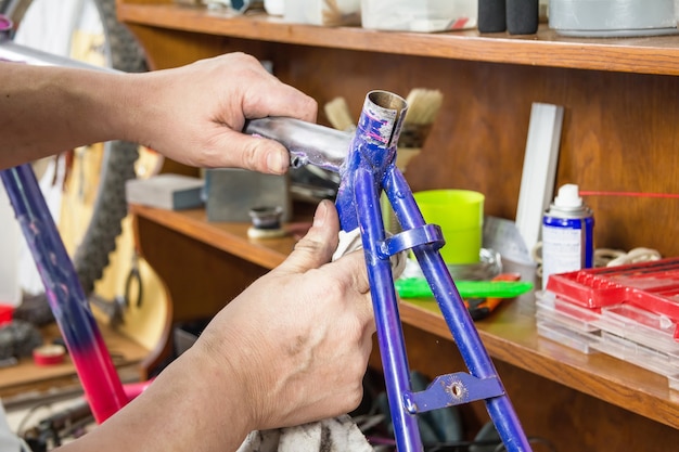 Manos de mecánico de bicicletas limpieza bicicleta marco dañado en un taller