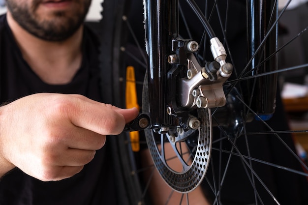 Manos de un mecánico que ajusta la rueda de una bicicleta