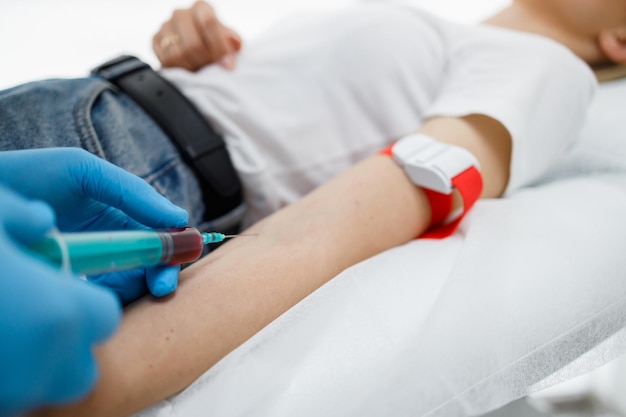 Manos del médico inyectando jeringa en la mano del paciente durante el análisis de sangre