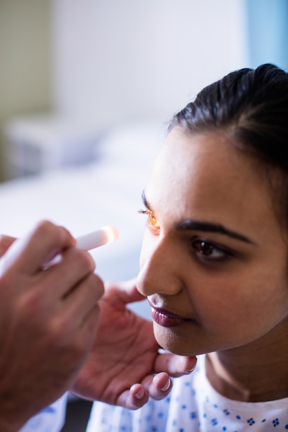 Manos del médico masculino que examina los ojos del paciente femenino