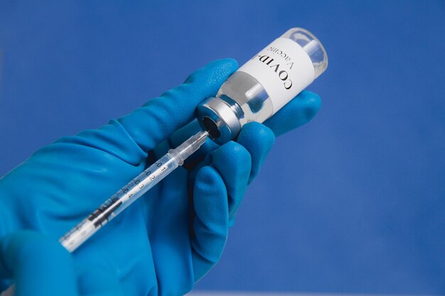 Manos de un médico o enfermera con guantes médicos azules que extraen una jeringa con la vacuna covid19 de un vial de cerca Concepto de vacunación contra el coronavirus