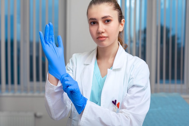 Manos del médico poniéndose guantes de látex en un hospital Mujer en bata de médico con guantes de látex Protección contra virus y bacterias Covid 19 Health.