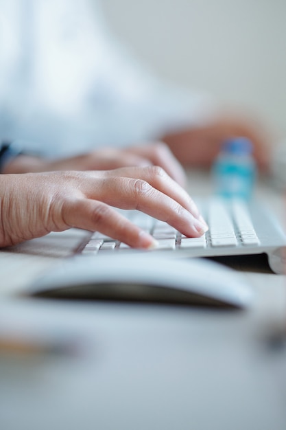 Manos del médico trabajando en una computadora en la oficina del hospital e ingresando los datos de los pacientes en forma especial