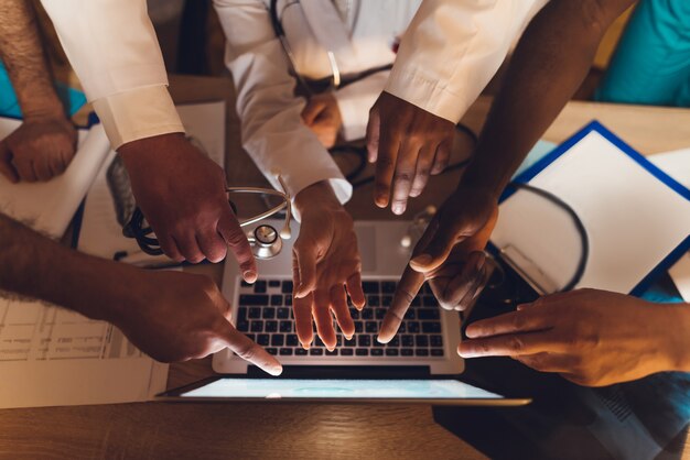 Las manos de los médicos de diferentes razas se muestran en la computadora portátil.