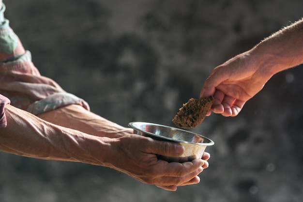 Manos de mendigo masculino en busca de comida o dinero con monedas de estaño de bondad humana en la madera