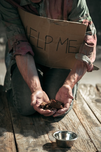 Manos de mendigo masculino en busca de dinero con el signo de AYUDARME de la bondad humana en el piso de madera en la vía pública o pasarela de la calle. Pobres sin hogar en la ciudad. Problemas con las finanzas, lugar de residencia.