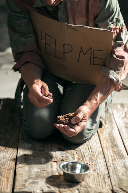 Manos de mendigo masculino buscando dinero en el piso de madera en la vía pública