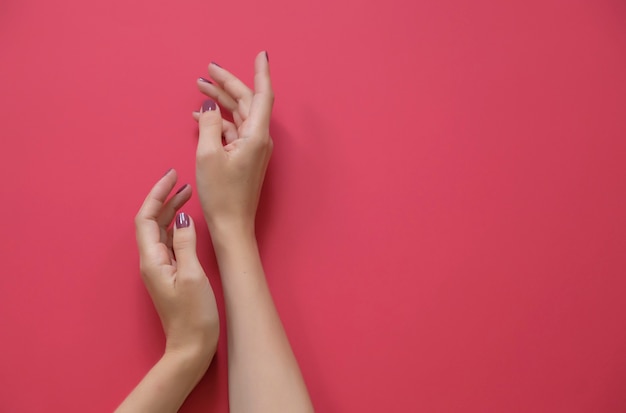 Foto las manos de moda elegantes de la mujer en fondo rojo