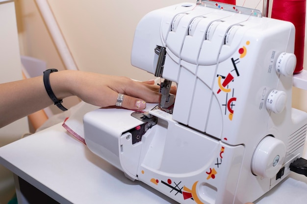 Las manos de modista cosen telas en una máquina de coser