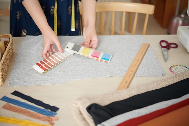 Manos de modista usando la paleta de colores al elegir el color del forro para la prenda