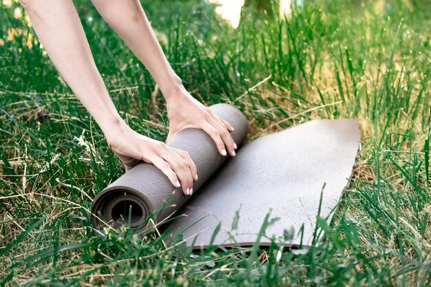 Manos de mujer abriendo la estera de yoga al aire libre en el parque