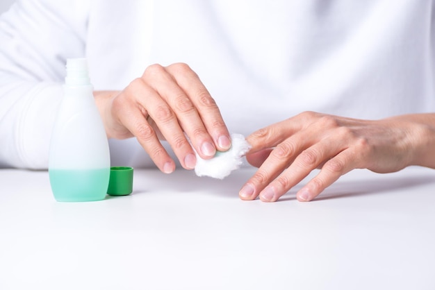 Manos de mujer adulta quitando esmalte de uñas de sus uñas manicura casera belleza de manos