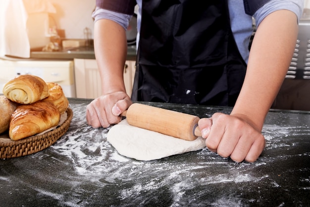 Las manos de la mujer amasan la masa con harina, huevos e ingredientes. en la cocina