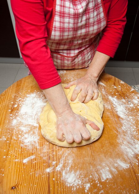 Las manos de la mujer amasan la masa en la mesa de madera