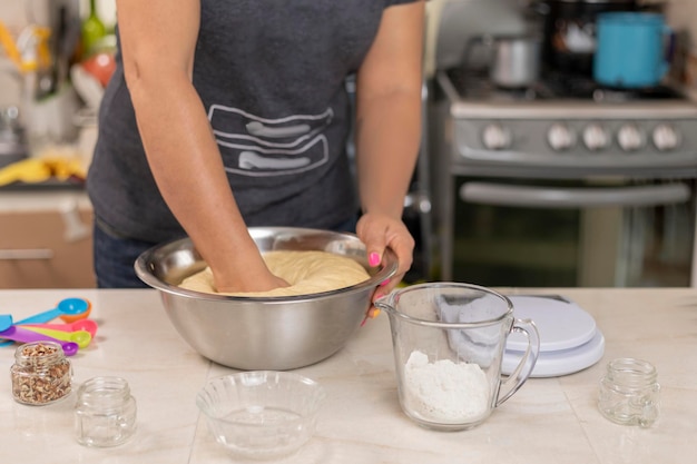 Manos de mujer amasando ingredientes para hacer pan de muerto