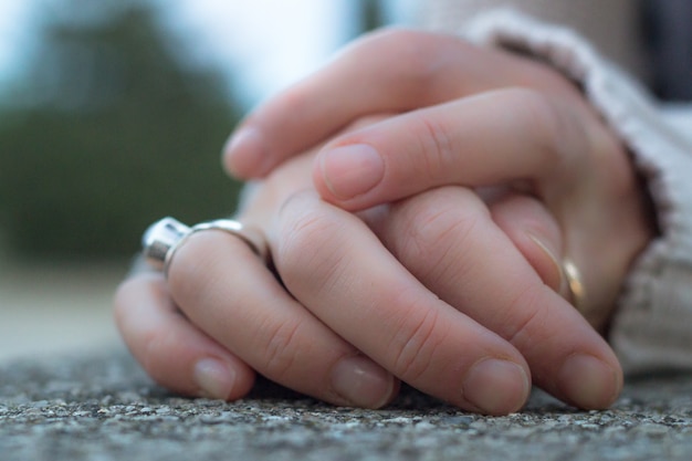 Manos de mujer con anillo de plata descansando sobre una piedra