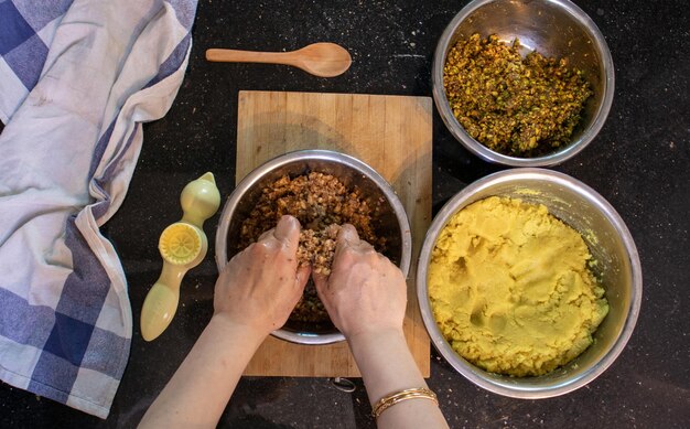 Manos de mujer árabe mientras prepara ingredientes y masa de almendras para keto kahk en casa