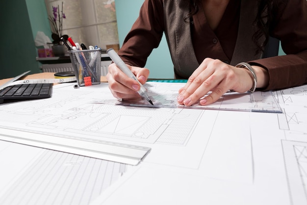 Manos de mujer arquitecta trabajando en planos en su escritorio. Negocios y creatividad. trabajo de arquitectura