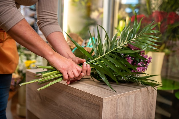 Manos de una mujer arreglando un ramo de flores sobre una mesa